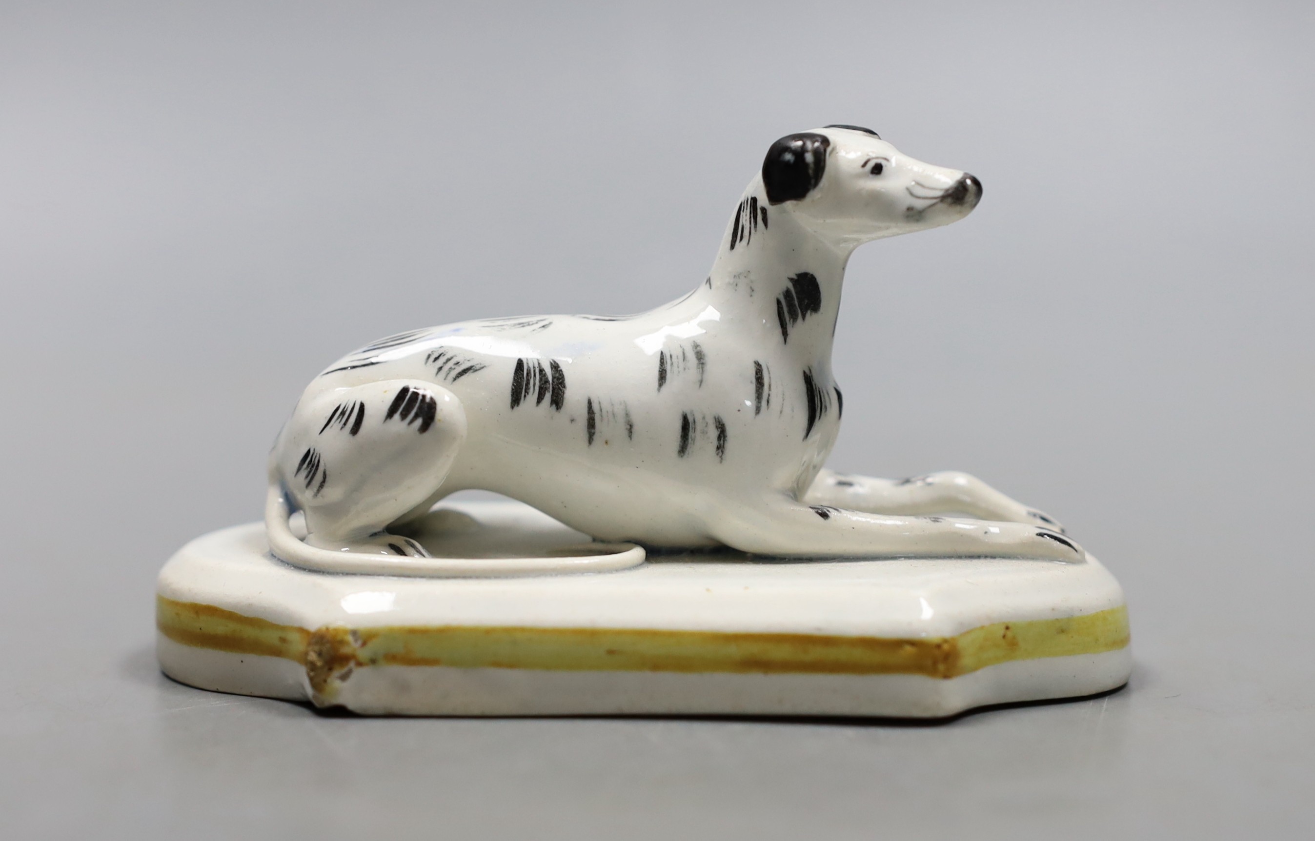 A Staffordshire porcelain model of a recumbent greyhound, c.1830–50, with black markings to its fur, 10.2 cm long, Provenance- Dennis G Rice collection